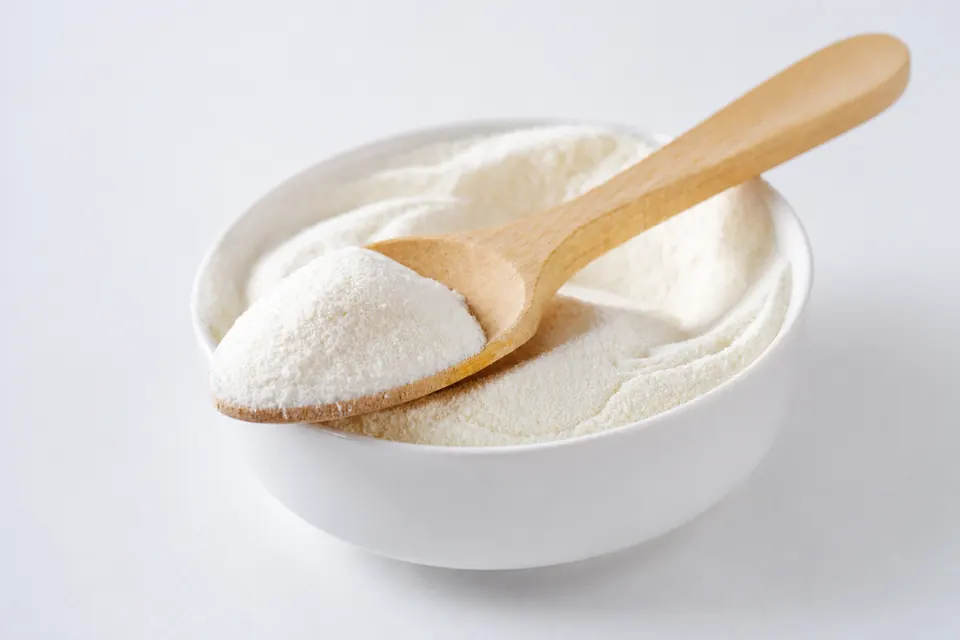 Fine whey fermentate powder in a wooden spoon and white bowl